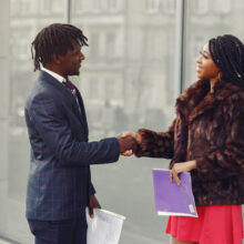 Black couple. Woman in a red dress. Man in a suit. Businesspeople.